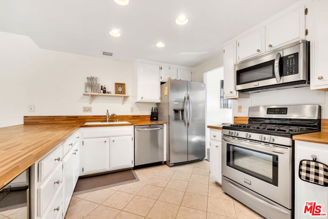 kitchen featuring stainless steel appliances, sink, wooden counters, and white cabinets