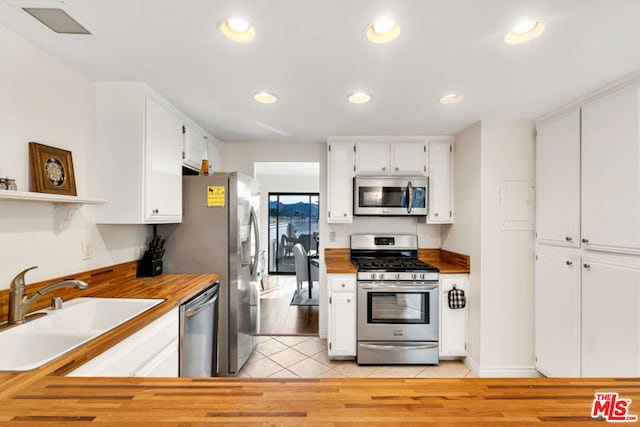 kitchen with sink, stainless steel appliances, white cabinets, and light tile patterned flooring