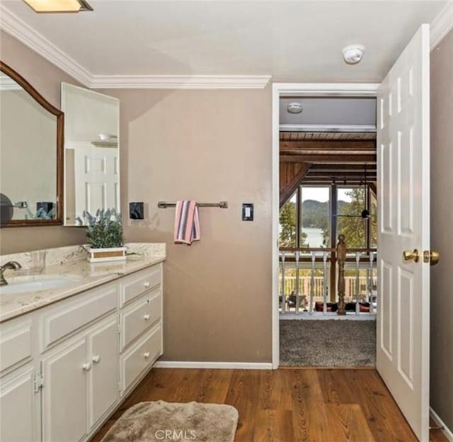 bathroom featuring wood-type flooring, ornamental molding, and vanity