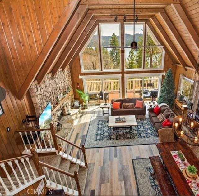 living room with hardwood / wood-style flooring, wooden walls, high vaulted ceiling, and ceiling fan