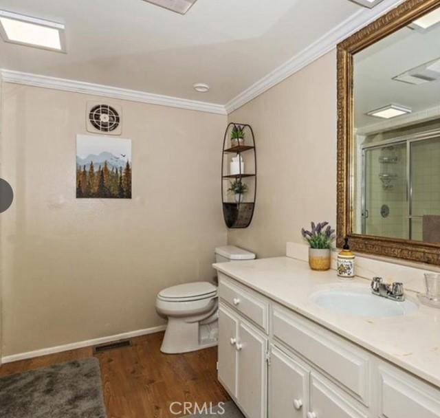 bathroom with hardwood / wood-style flooring, vanity, ornamental molding, an enclosed shower, and toilet