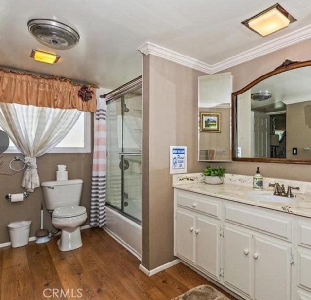 full bathroom with bath / shower combo with glass door, hardwood / wood-style flooring, vanity, toilet, and crown molding