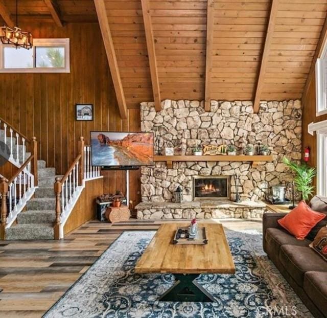 living room with a fireplace, wood ceiling, wooden walls, and beamed ceiling