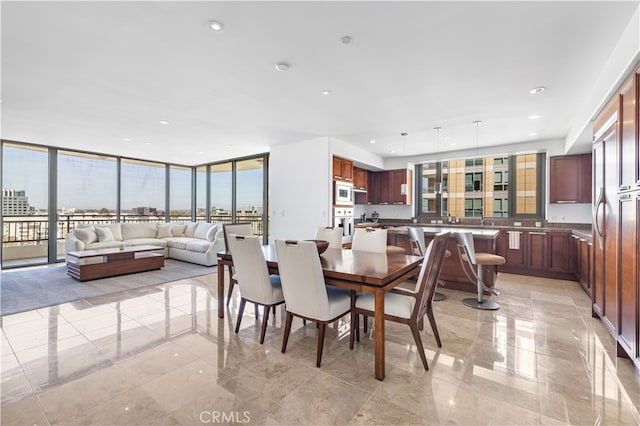 dining area with marble finish floor, recessed lighting, a view of city, and a wall of windows