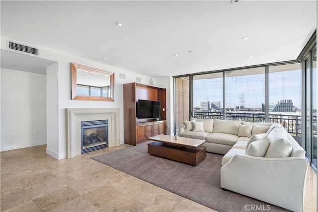 living area with baseboards, visible vents, recessed lighting, expansive windows, and a glass covered fireplace