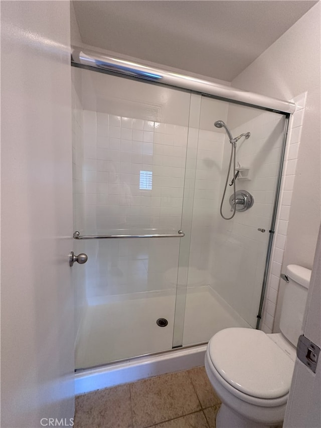 bathroom with an enclosed shower, tile patterned flooring, and toilet