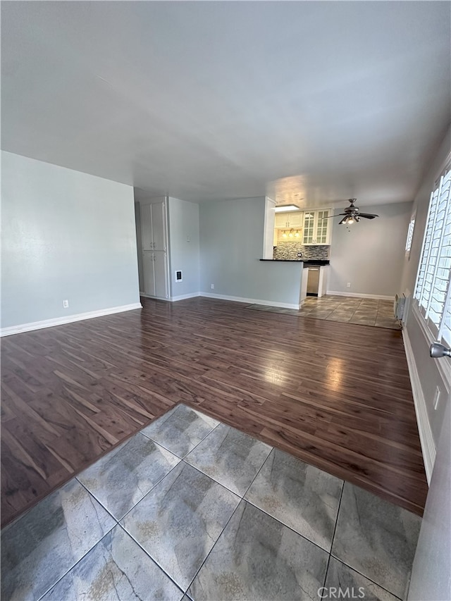 unfurnished living room with dark hardwood / wood-style floors and ceiling fan