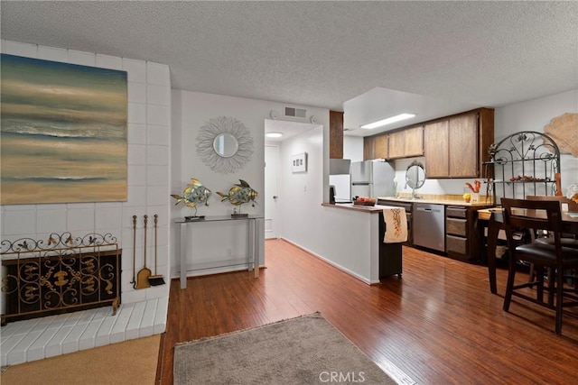 kitchen featuring dark wood-type flooring, stainless steel dishwasher, white fridge, and a textured ceiling