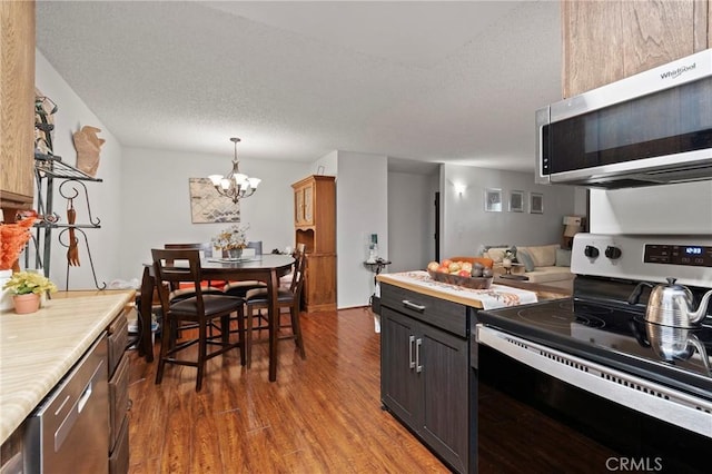 kitchen with appliances with stainless steel finishes, dark wood-type flooring, pendant lighting, and a textured ceiling