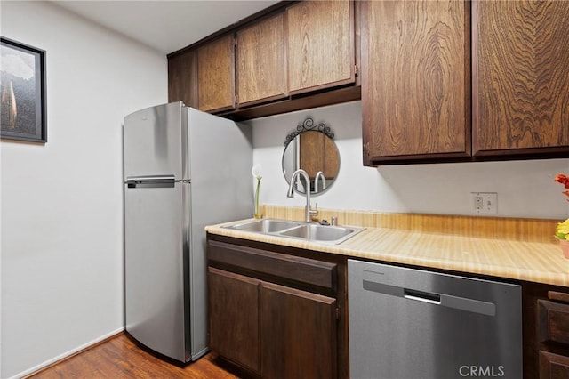 kitchen with dark brown cabinets, appliances with stainless steel finishes, sink, and hardwood / wood-style floors