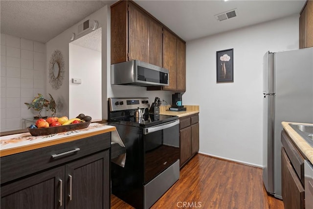 kitchen featuring appliances with stainless steel finishes, a textured ceiling, and dark hardwood / wood-style flooring