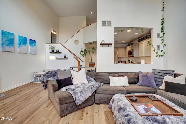 living room featuring a towering ceiling and light hardwood / wood-style flooring