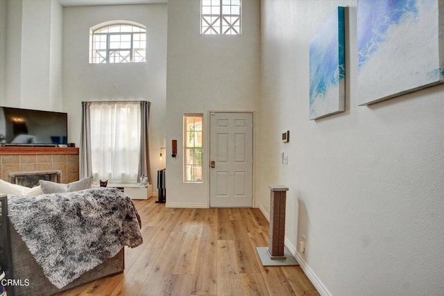 entrance foyer with a towering ceiling, a tile fireplace, and light hardwood / wood-style flooring