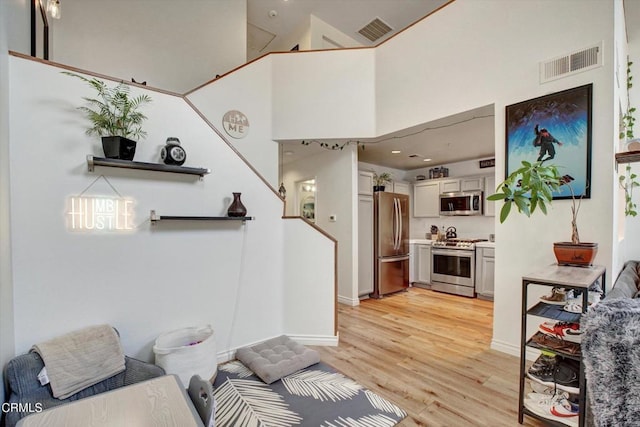 living room featuring a towering ceiling and light hardwood / wood-style floors