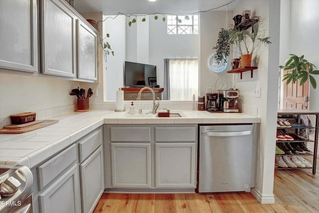 kitchen featuring sink, tile countertops, light hardwood / wood-style floors, and dishwasher