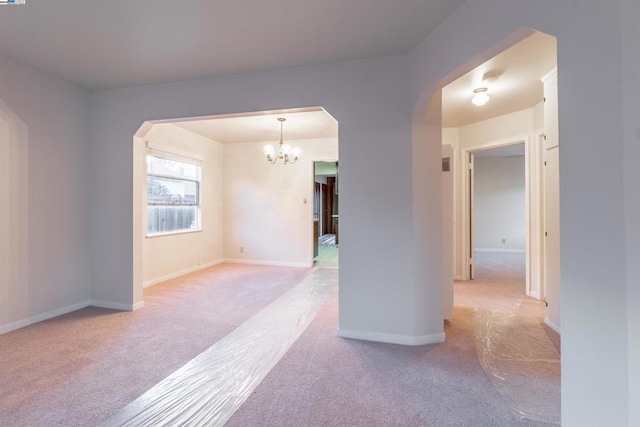 carpeted empty room featuring a chandelier