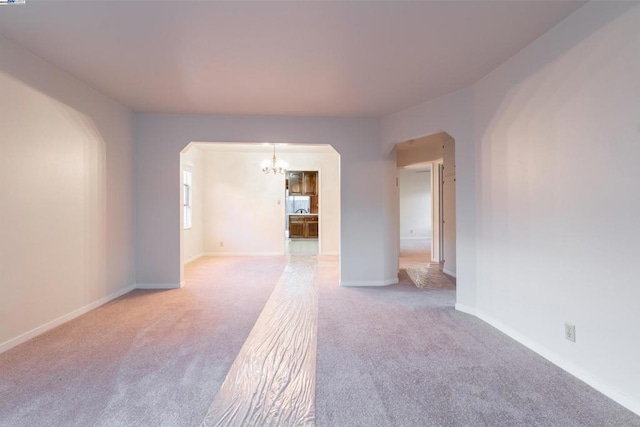 carpeted empty room with a chandelier