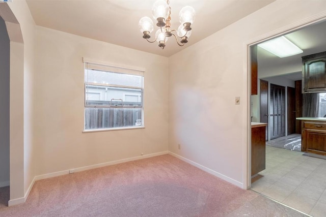 unfurnished room featuring a chandelier and light carpet