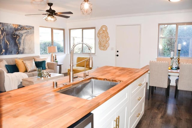 kitchen featuring crown molding, wooden counters, sink, and white cabinets