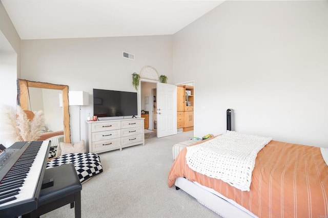 bedroom featuring ensuite bathroom, light carpet, and high vaulted ceiling