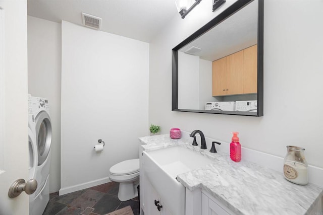 bathroom featuring vanity, washer / dryer, and toilet