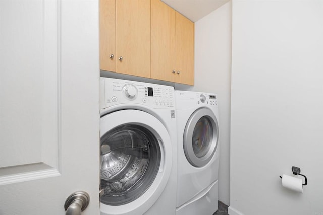 laundry area with separate washer and dryer and cabinets