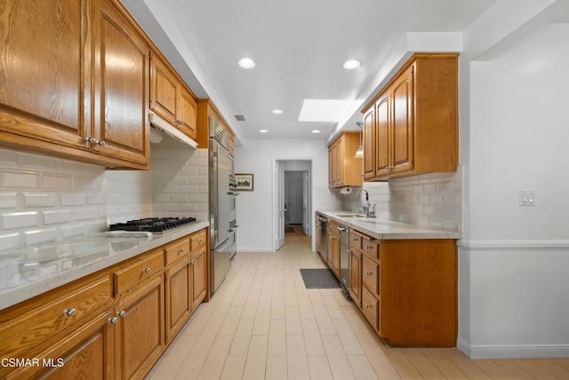 kitchen with tasteful backsplash, stainless steel appliances, a skylight, and sink