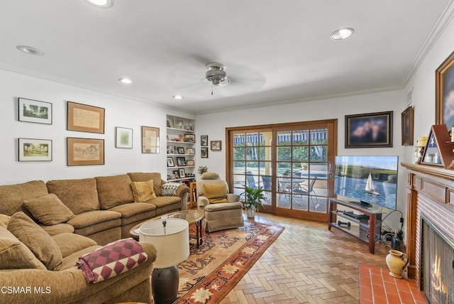 living room with crown molding, ceiling fan, a brick fireplace, built in shelves, and light parquet flooring