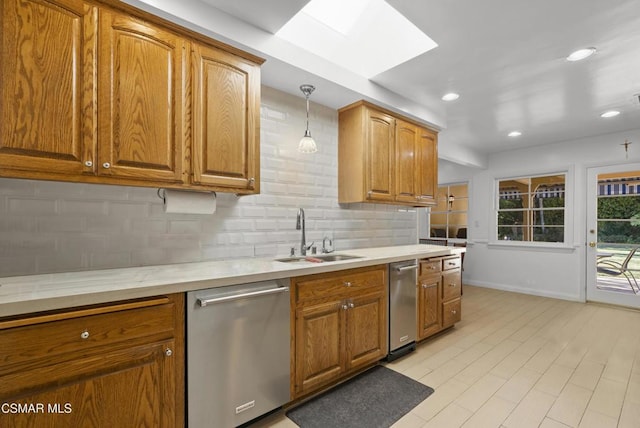 kitchen featuring sink, a skylight, dishwasher, pendant lighting, and backsplash