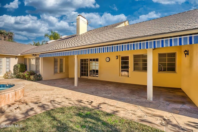 rear view of property with a hot tub and a patio