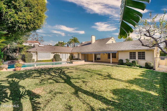 rear view of house featuring a fenced in pool, a patio, and a lawn