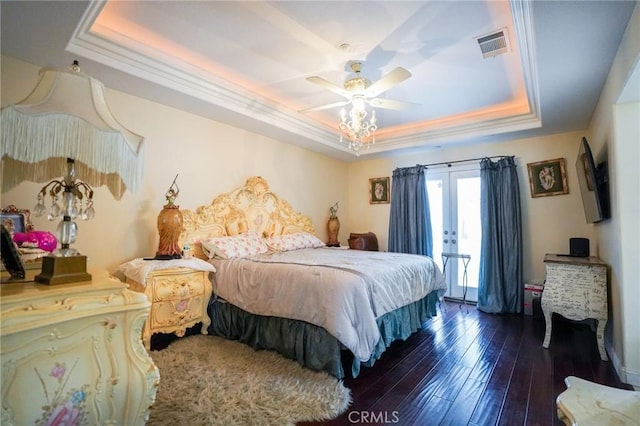 bedroom with a tray ceiling, dark wood-type flooring, french doors, and ceiling fan