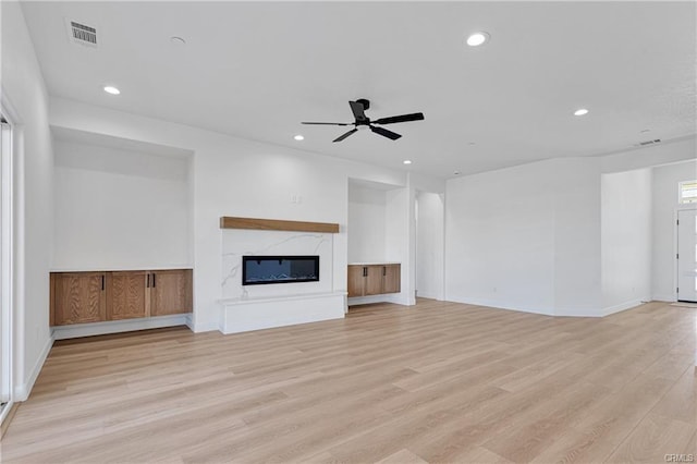 unfurnished living room featuring light hardwood / wood-style floors, a premium fireplace, and ceiling fan