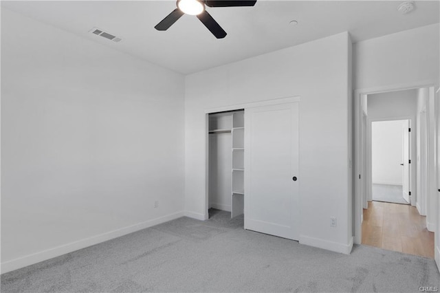 unfurnished bedroom with light colored carpet, a closet, and ceiling fan