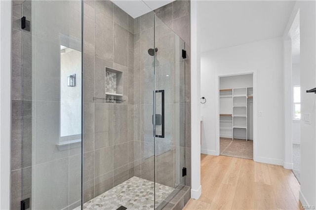 18554 Temecula Ave, Hesperia, CA 92345 - full bathroom featuring a stall shower, wood finished floors, a walk in closet, and baseboards