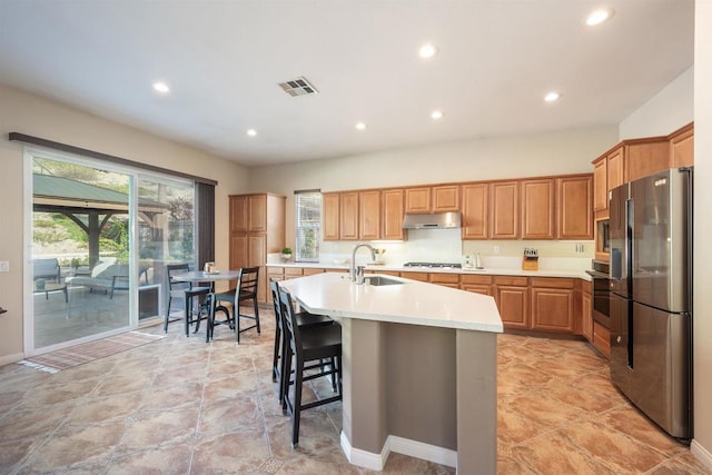 kitchen featuring stainless steel appliances, a kitchen island with sink, sink, and a kitchen breakfast bar