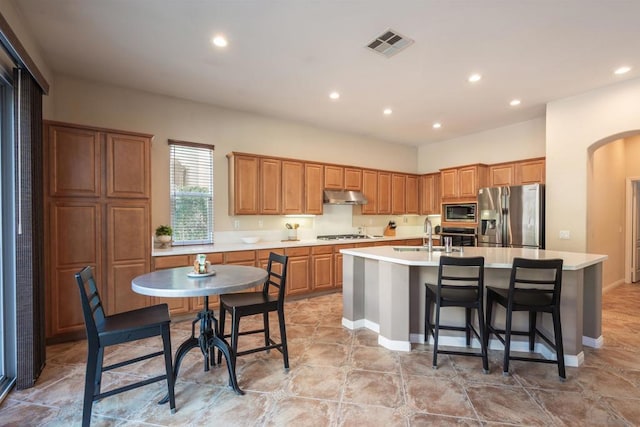 kitchen featuring appliances with stainless steel finishes, a kitchen bar, sink, and a center island with sink