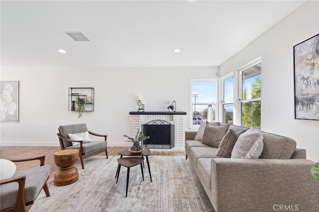 living room with a brick fireplace and light hardwood / wood-style flooring