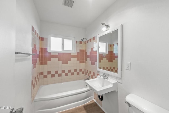 full bathroom with tiled shower / bath, wood-type flooring, sink, and toilet