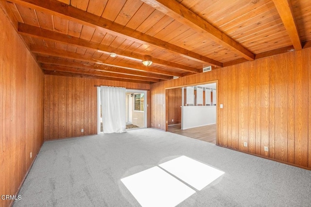 spare room featuring beamed ceiling, carpet floors, wooden ceiling, and wooden walls