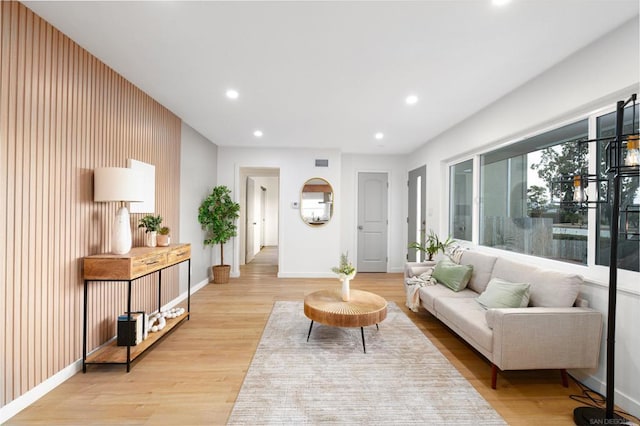 living room with light hardwood / wood-style flooring and wooden walls