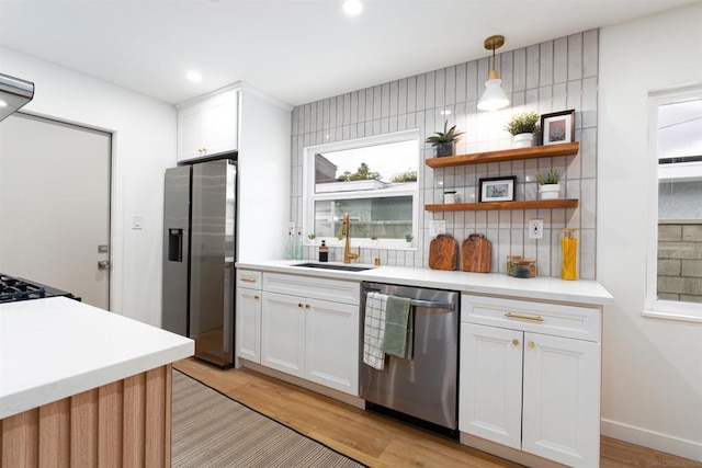 kitchen featuring sink, decorative light fixtures, white cabinets, and appliances with stainless steel finishes