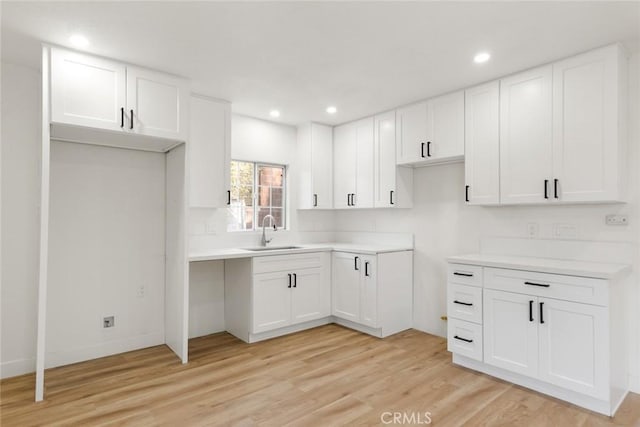 kitchen with white cabinetry, light hardwood / wood-style floors, and sink