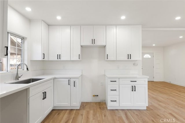 kitchen with light hardwood / wood-style floors, sink, and white cabinets