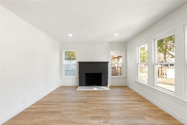 unfurnished living room featuring a fireplace and light hardwood / wood-style floors