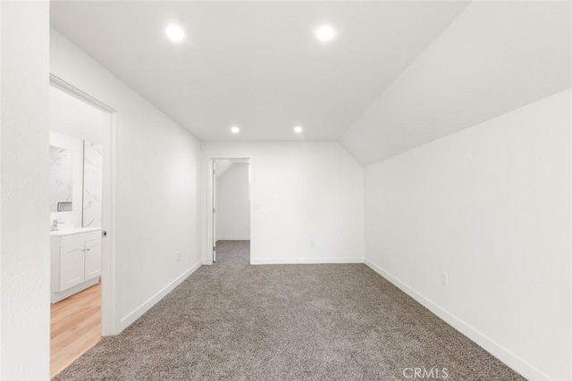 additional living space with light colored carpet and vaulted ceiling