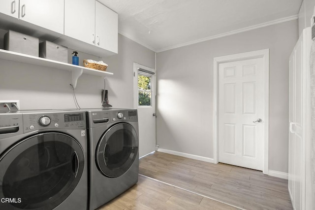 laundry area featuring cabinets, ornamental molding, washer and dryer, and light hardwood / wood-style flooring