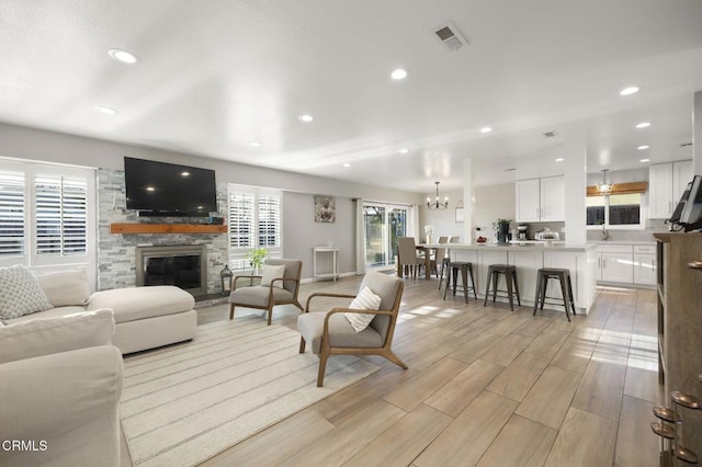 living room featuring a stone fireplace and a notable chandelier