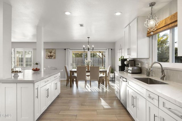 kitchen with tasteful backsplash, sink, hanging light fixtures, and white cabinets