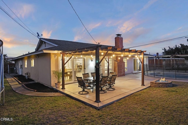 back house at dusk with central AC unit, a yard, a pergola, and a patio